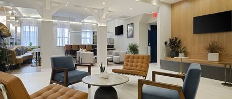 A spacious lobby with a round coffee table, several seating areas, and a reception desk.