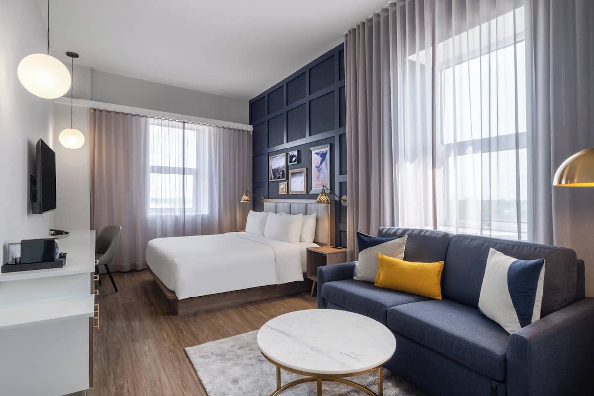 Een moderne hotelkamer met een bed, bank, televisie en bureau.