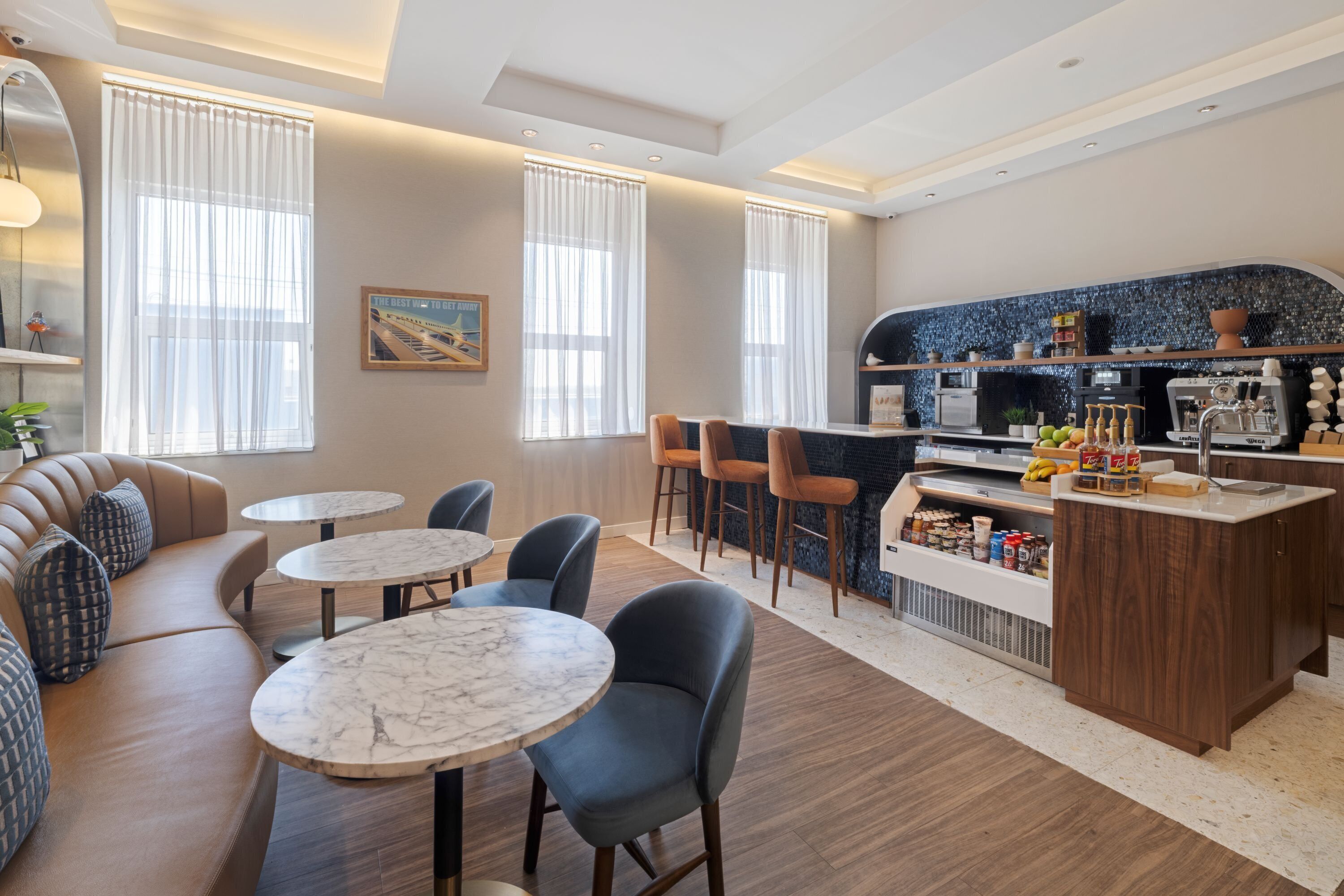 Un hall d’hôtel moderne doté d’un espace salon, d’un bar et d’un coin café.