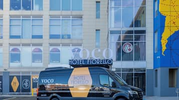 A black van with "Hotel Fiorrello" branding parked in front of a building with large windows and a blue map on the right side.