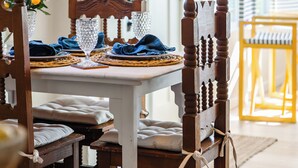 A dining table set with blue napkins, clear glassware, and a wooden chair with a decorative headboard. - "Lost Loon" Oceanfront Cottage by Roxy Rentals (Englewood)