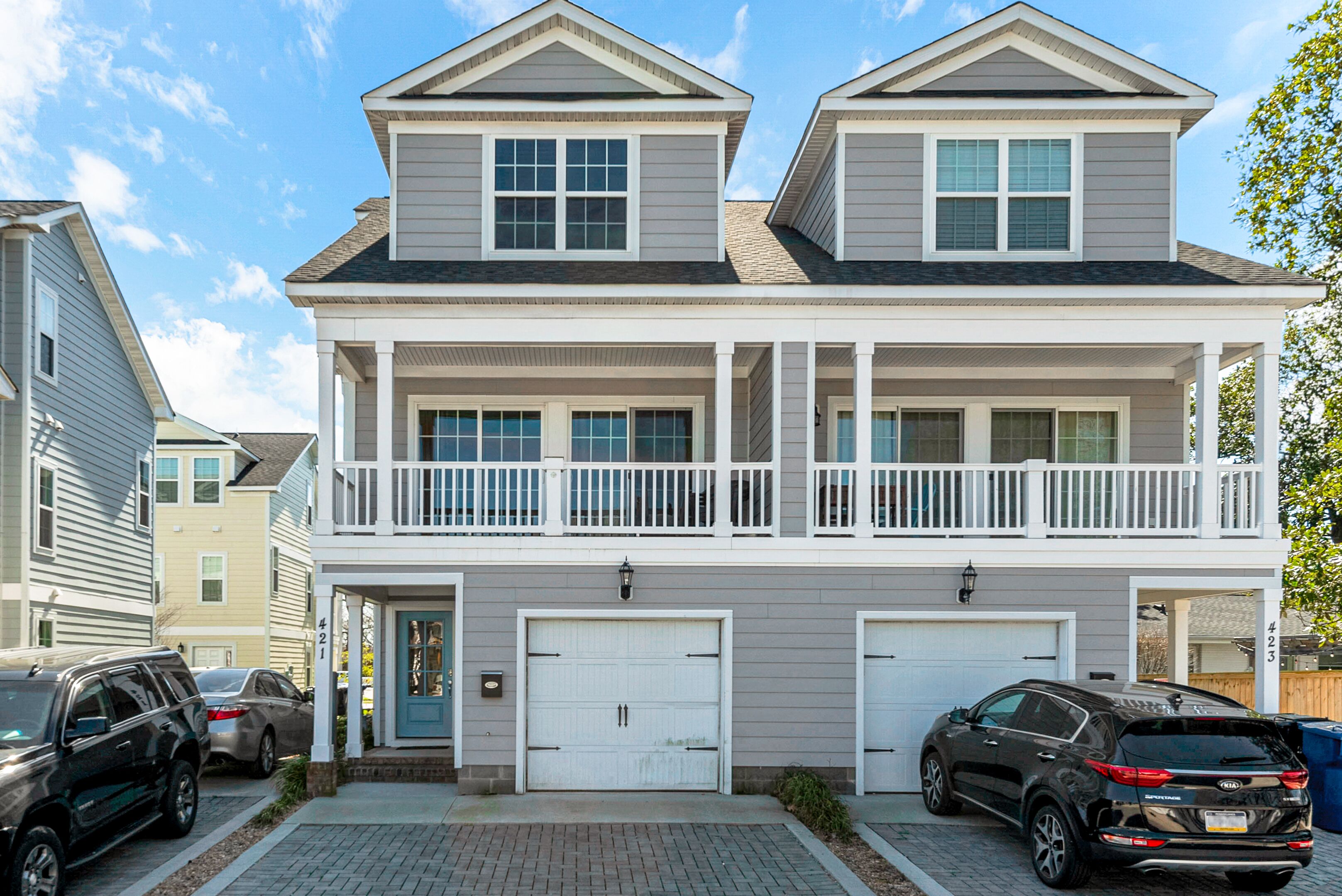 A two-story residential building with a front porch, two garages, and a balcony.