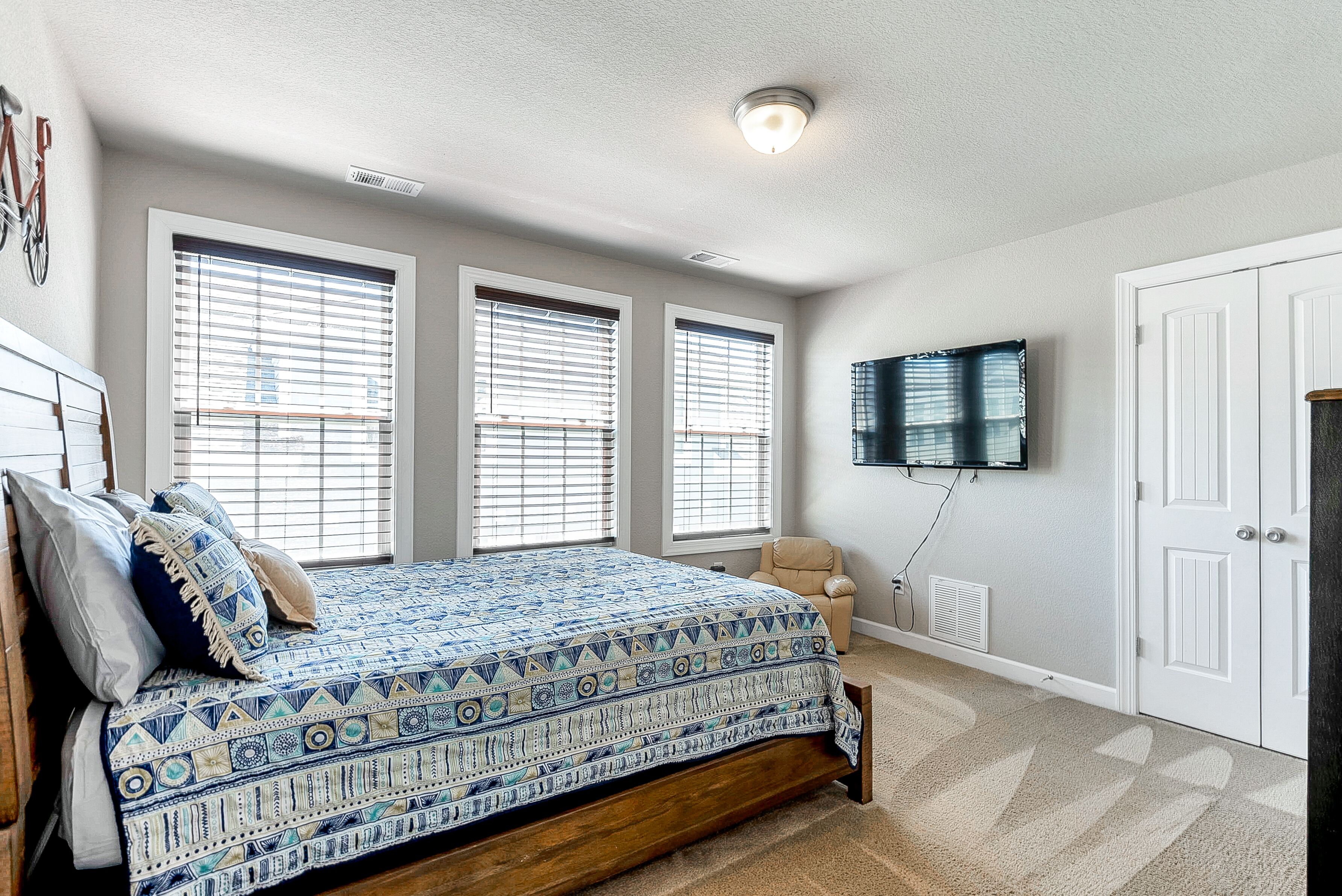 A bedroom with a bed, a television mounted on the wall, and a door.