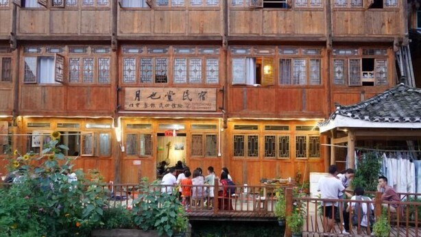 Un bâtiment traditionnel en bois, doté de plusieurs balcons et d’une enseigne indiquant qu’il s’agit d’une maison d’hôtes.