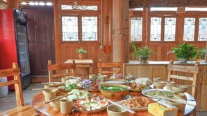 Un coin repas en bois, avec une table ronde dressée pour le repas, entourée de chaises en bois.