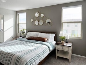 A bedroom with a bed, bedside tables, a wall-mounted mirror, and a window. - Desert Azure - Escape to the Desert (Coachella)