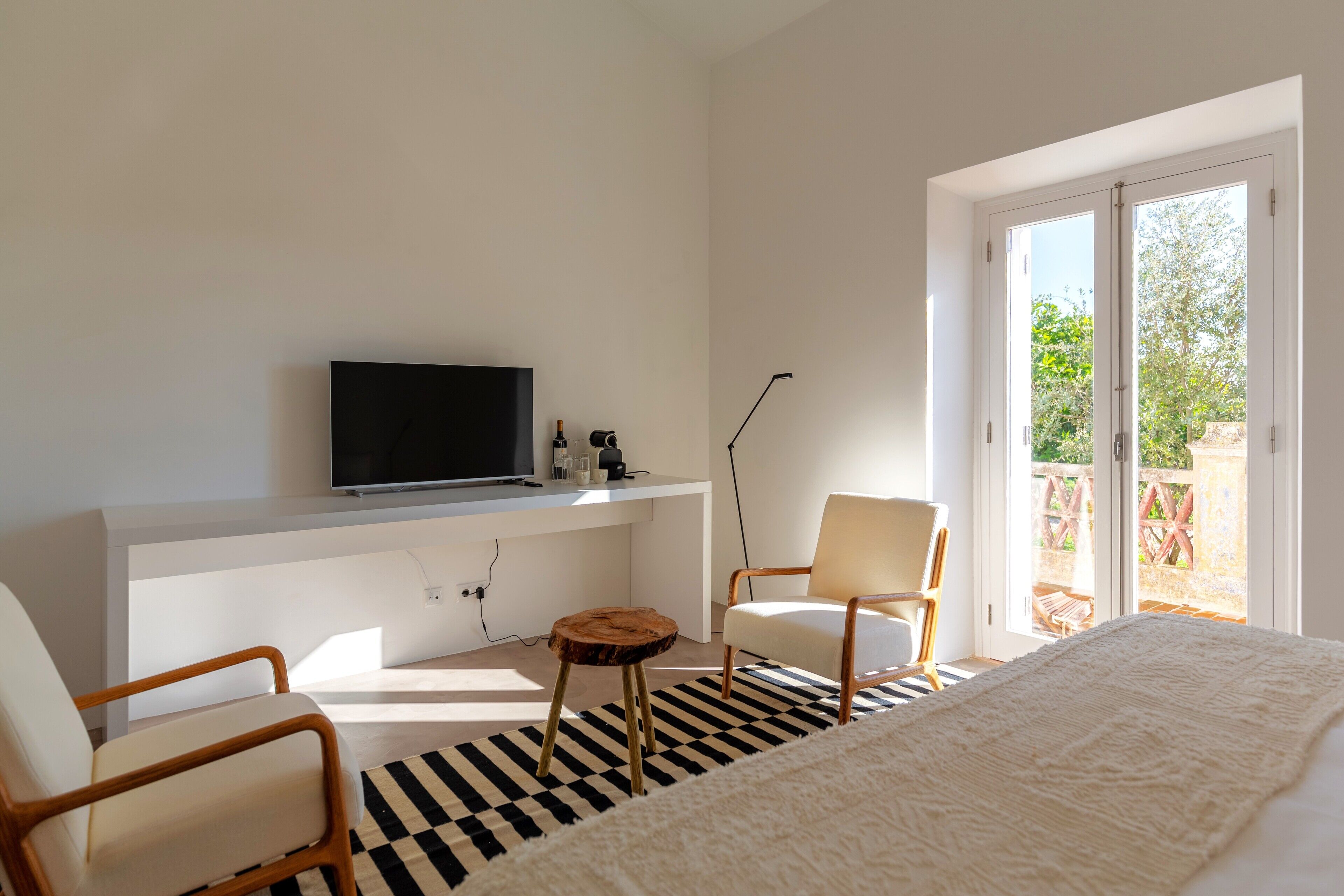 Un dormitorio moderno con cama, televisor, escritorio y silla.