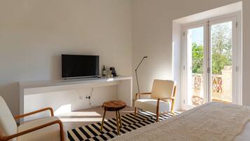 Un dormitorio moderno con cama, televisor, escritorio y silla.