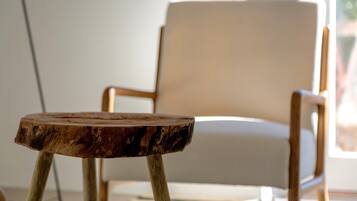 A wooden table with a natural finish in a room with a white chair and a window.