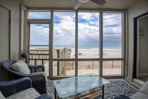 A room with large windows overlooking a beach, wicker furniture, and a glass table. - PRIVATE WALKWAY TO THE BEACH, ONE OF THE FEW ON THE GRAND STRAND! (Surfside Beach)