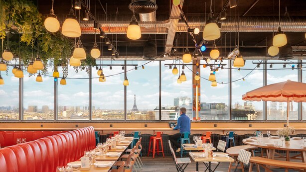 Un restaurante con vistas a la Torre Eiffel, con asientos rojos y lámparas colgantes.
