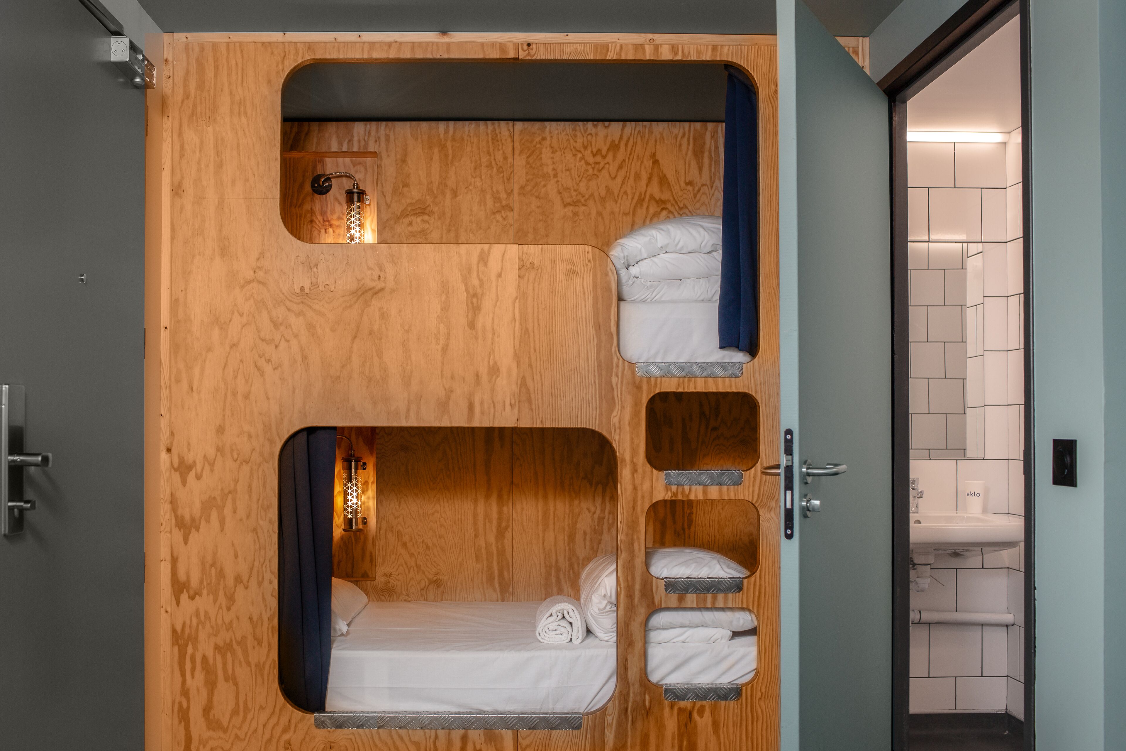 A compact room with a bunk bed, a small window, and a bathroom visible through an open door.