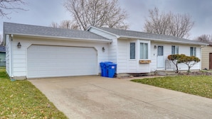 A single-story house with a white garage door, a small front porch, and a tree in the yard. - Cozy Sioux Falls Home - 7 Mi to Downtown! (Sioux Falls)