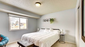 A bedroom with a bed, a chair, a small table, a window, and a ceiling light. - Cozy Sioux Falls Home - 7 Mi to Downtown! (Sioux Falls)