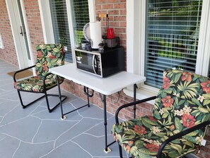 A patio area with a table and two chairs, a microwave, and a red cup. - Island's Sunset Blue Guest Room on Lake Murray, Permit #2500877 (Chapin)