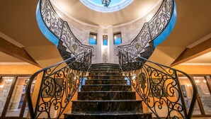 Eine prachtvolle Treppe mit aufwendiger schwarzer Metallgalerie und Marmorstufen, die zu einem runden Oberlicht führt.
