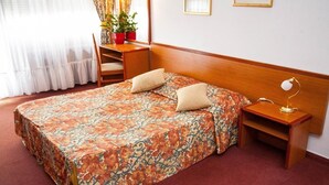 Un letto rifatto con una coperta a fiori, un comodino con una lampada e una sedia.