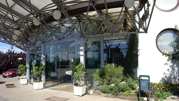 Un edificio moderno con ingresso in vetro, struttura in metallo e piante ornamentali.