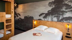 A bedroom with a bed, a wooden headboard, a mural of trees, and two wall-mounted lights. - Eklo Hotels Montpellier City center Saint-Roch train station (Montpellier)