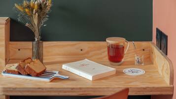 Ein Holztisch mit einem Buch, einer Tasse, einem Löffel und einer Vase mit getrockneten Blumen.