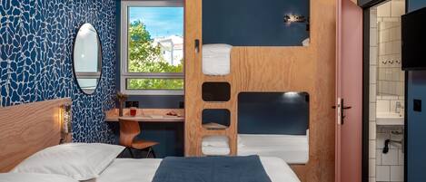 Una habitación con literas, un escritorio, una silla, un espejo y una ventana.