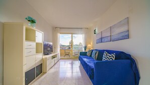 Ein Wohnzimmer mit einem blauen Sofa, einem Fernseher und einem Schrank.