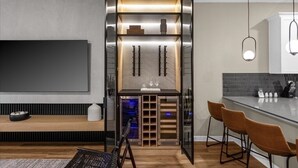 Una cocina moderna con una cava empotrada, taburetes de bar y un televisor de pantalla plana grande.