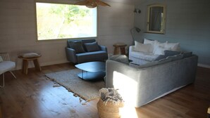 A modern living room with a grey sofa, a blue armchair, and a small coffee table. There is a large window providing natural light, and a wooden floor. - Superb Belliloise house - high standing (Bangor)