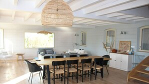 A modern kitchen with a wooden dining table and chairs, a hanging light fixture, and a view of the outdoors. - Superb Belliloise house - high standing (Bangor)