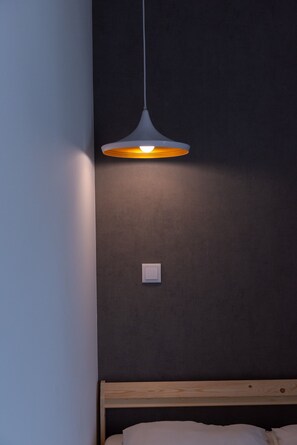 A room with a wooden bed, a dark wall, and a hanging pendant light. - Dude Beach Hostel (Figueira da Foz)