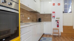 Uma cozinha moderna com armários brancos, eletrodoméstico amarelo e tapete com padrão azul.