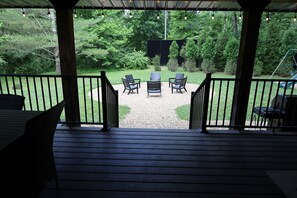 A covered patio with a view of a backyard, featuring a seating area with chairs and a table.