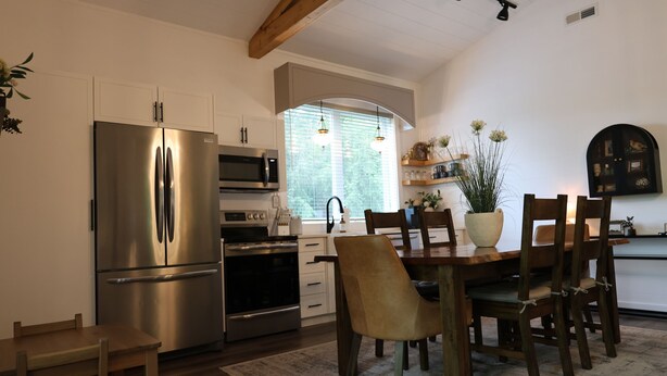 A modern kitchen with stainless steel appliances, wooden dining table, and chairs.