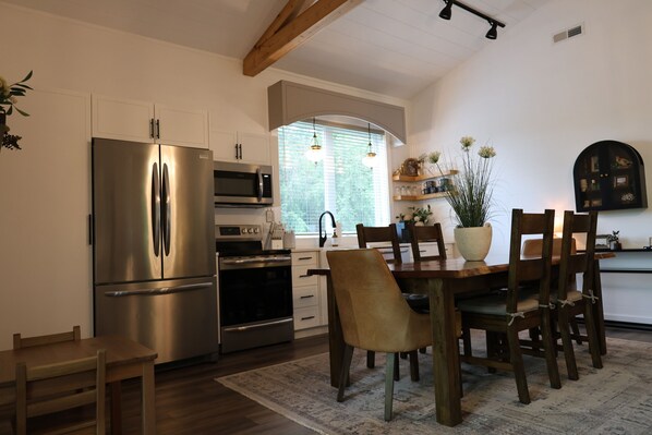 Una cocina moderna con electrodomésticos de acero inoxidable, una mesa de comedor de madera y sillas.