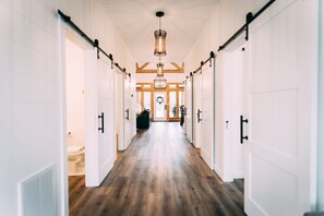 Stylish hallway with white doors, wooden floor, and a large light fixture.