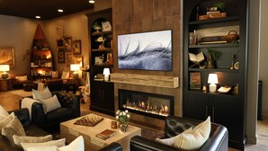 Una sala de estar con chimenea, sofás de cuero, una mesa de centro y una estantería con objetos decorativos.