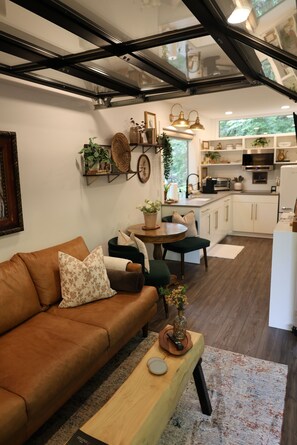 A modern living room with a brown sofa, a wooden coffee table, and a dining area with a green chair.