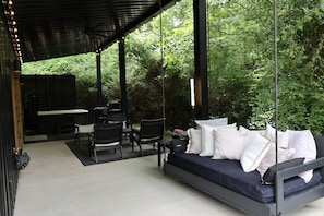 Un espace extérieur aménagé, abrité, avec un lit suspendu, des chaises et une table.