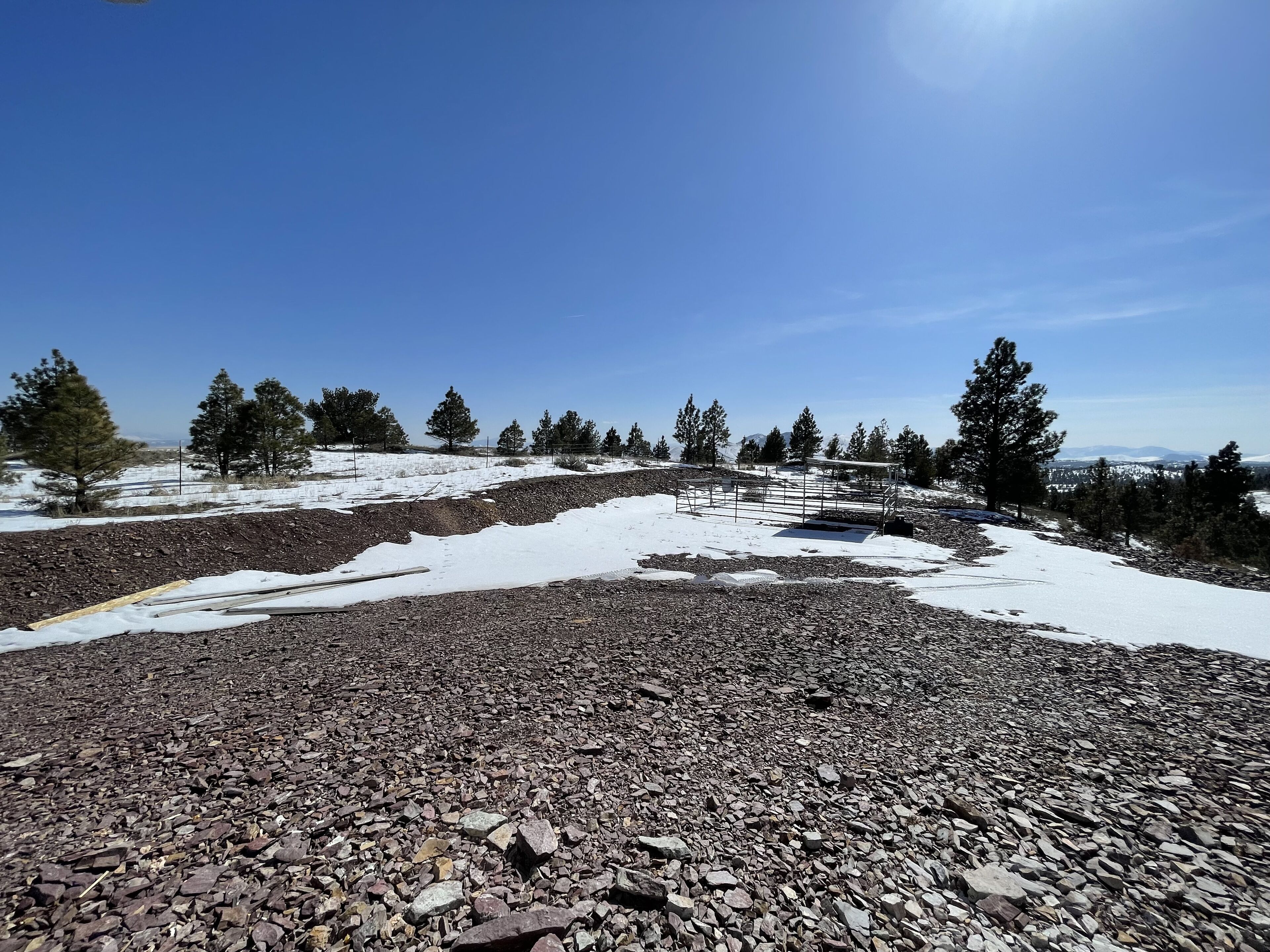 A rocky terrain with sparse snow patches and scattered trees.