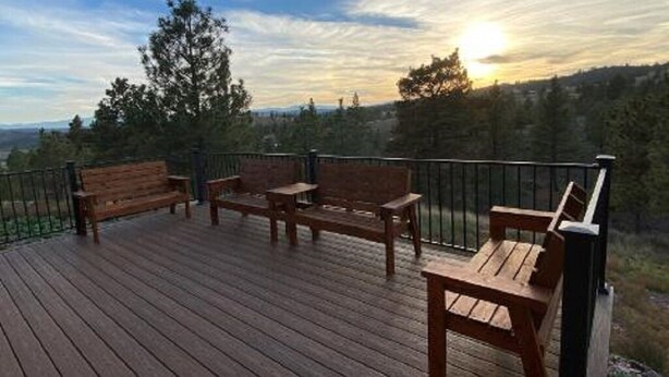 A wooden deck with benches and a table, overlooking a forested landscape. - SPORTSMAN'S PARADISE (Helena)