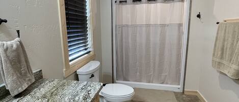A bathroom with a toilet, sink, and shower area.