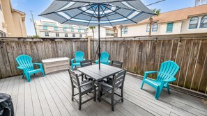 Eine Terrasse im Freien mit Tisch, Stühlen, einem Grill und einem großen Sonnenschirm.