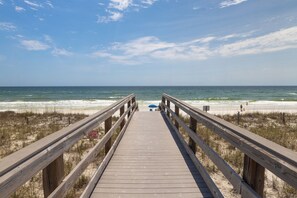 Un muelle de madera que conduce a una playa, con un cartel que dice 'KEEP OFF THE BEACH'.
