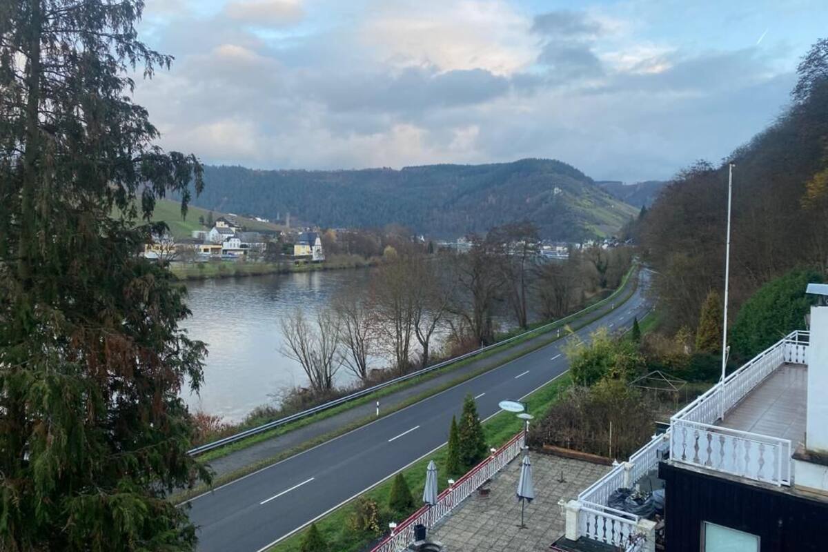 A river with a road alongside it, surrounded by trees and hills.