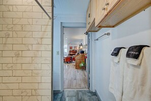 Un pasillo con pared de azulejos, un armario de madera y un perchero con toallas.