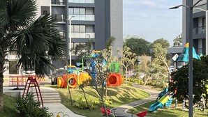 A playground with various play structures, a palm tree, and a building in the background. - 10Min. Del Aeropuerto apt.picina aire wifi 24H seguridad patio de juegos parqueo (Santiago De Los Caballeros)