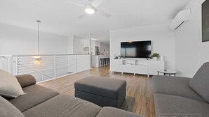 A modern living room with a flat-screen TV, grey sofas, and a ceiling fan. - Sunny Dais Beachfront - stunning views of the Marina, Clifftops and Port Vincent (Port Vincent)