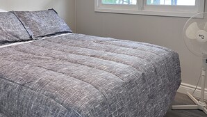 A bedroom with a bed, a window, and a standing fan. - Private getaway on Lower Buckhorn Lake (Trent Lakes)
