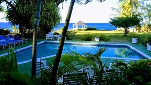 A swimming pool with a gazebo and lounge chairs in a tropical setting.