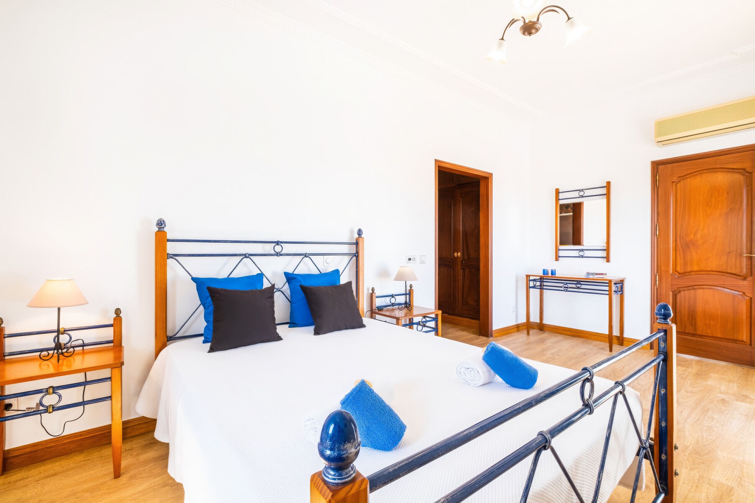 Una habitación de hotel con una cama, mesitas de noche, un escritorio, un espejo y un armario.